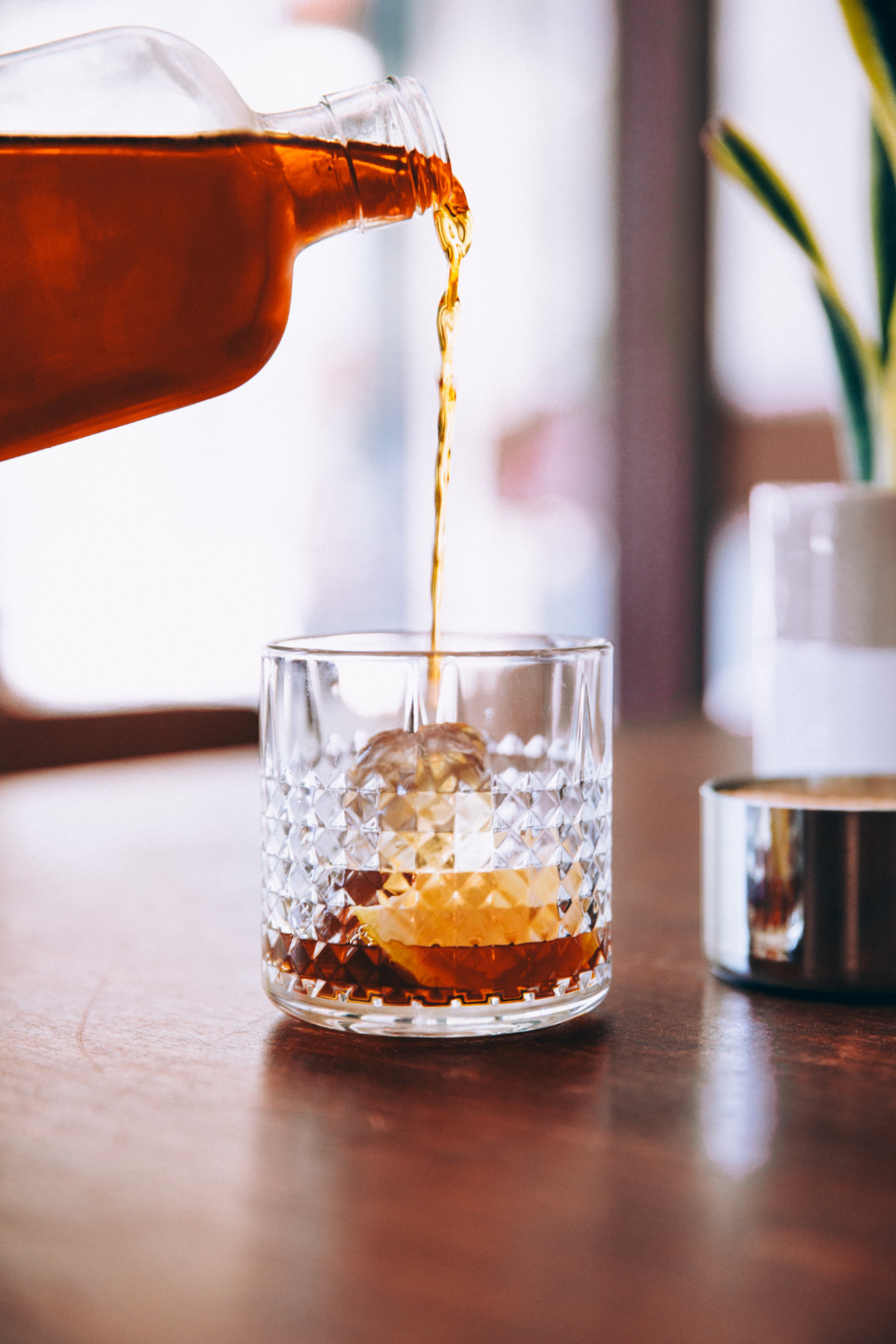 Distillato ambrato versato in un bicchiere con ghiaccio