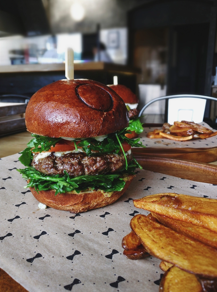 Burger artigianale con patate rustiche servito al tavolo di un pub